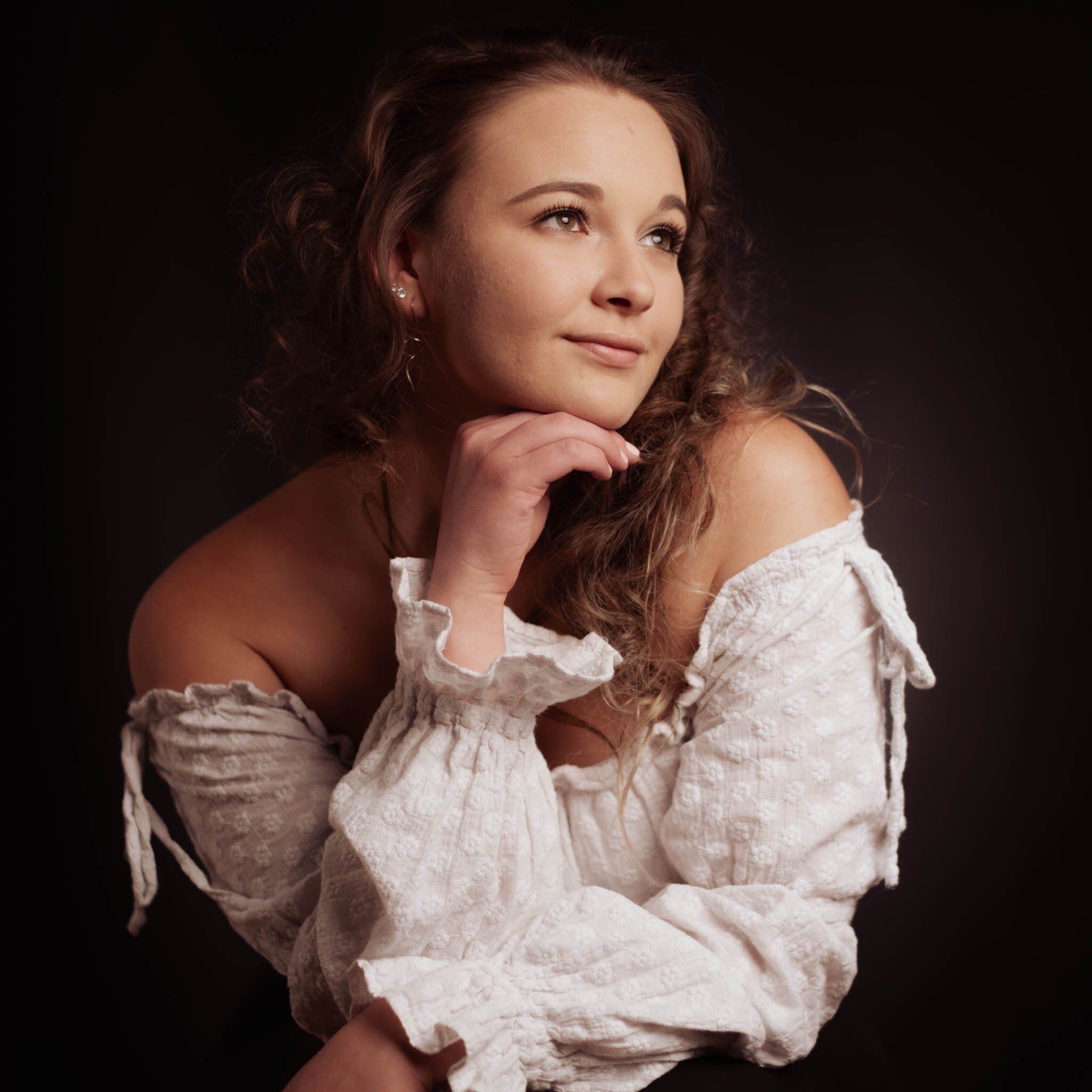 Portrait in white dress against dark backdrop